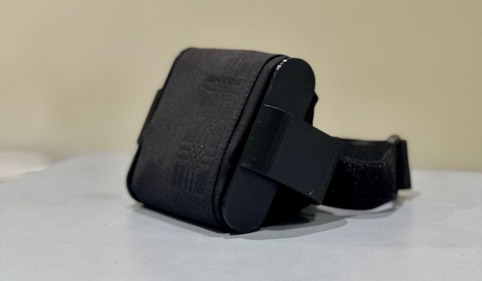 Side view of the final Design 1 upper-arm prototype showing its rounded 3D-printed wiping structure, wrapped handkerchief, and Velcro mounting strap.