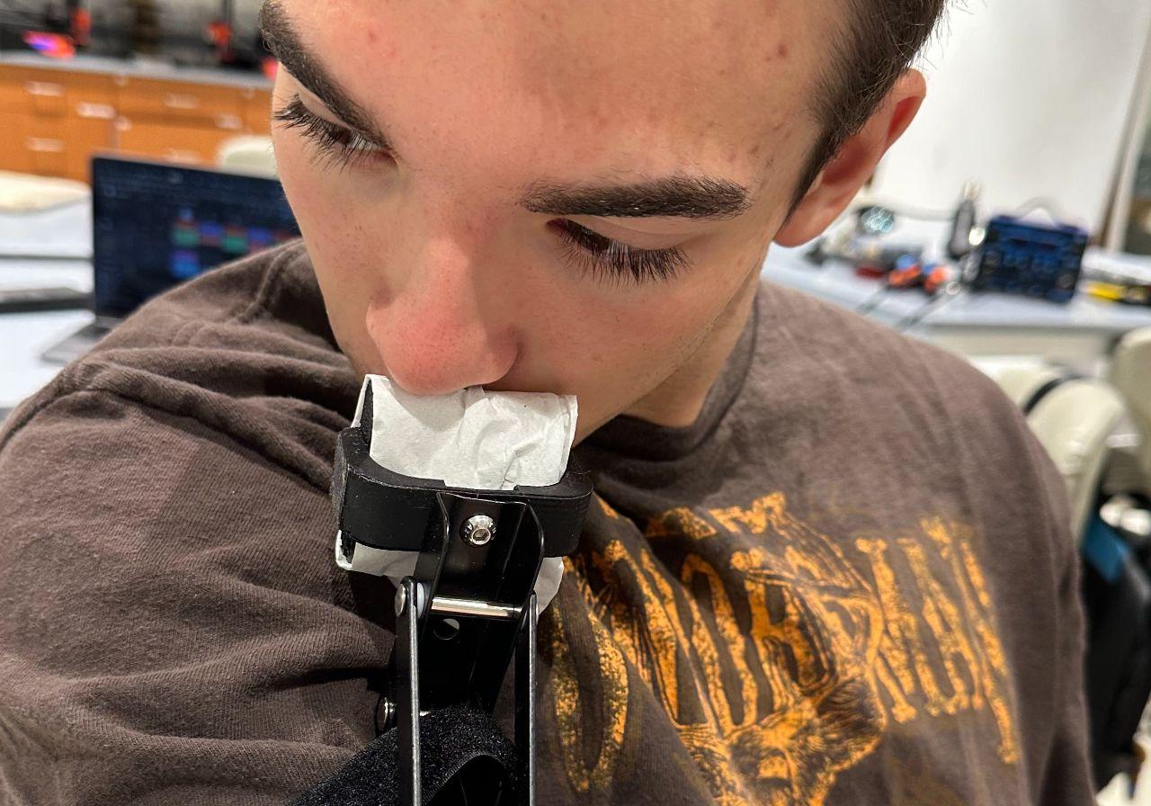 Design 2 forearm extension being evaluated in use, with two Velcro straps securing the rigid extension and its wiping surface near the face.